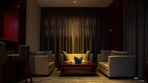 A modern living room with a sofa set, a coffee table, and a large window with curtains. - Daamat Hotel (Addis Ababa)