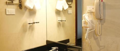 Un baño de hotel con lavabo, espejo, toallero y teléfono.