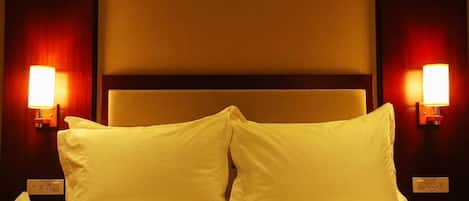 A hotel room with a bed, two bedside lamps, and a nightstand with a phone and a tissue box.