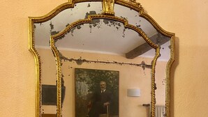 Una habitación con un espejo grande y ornamentado, un sofá y un cuadro en la pared.