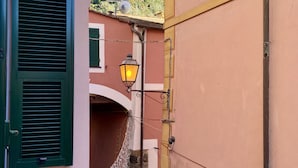 Un callejón estrecho entre edificios, con un farol rústico y un pequeño arco.