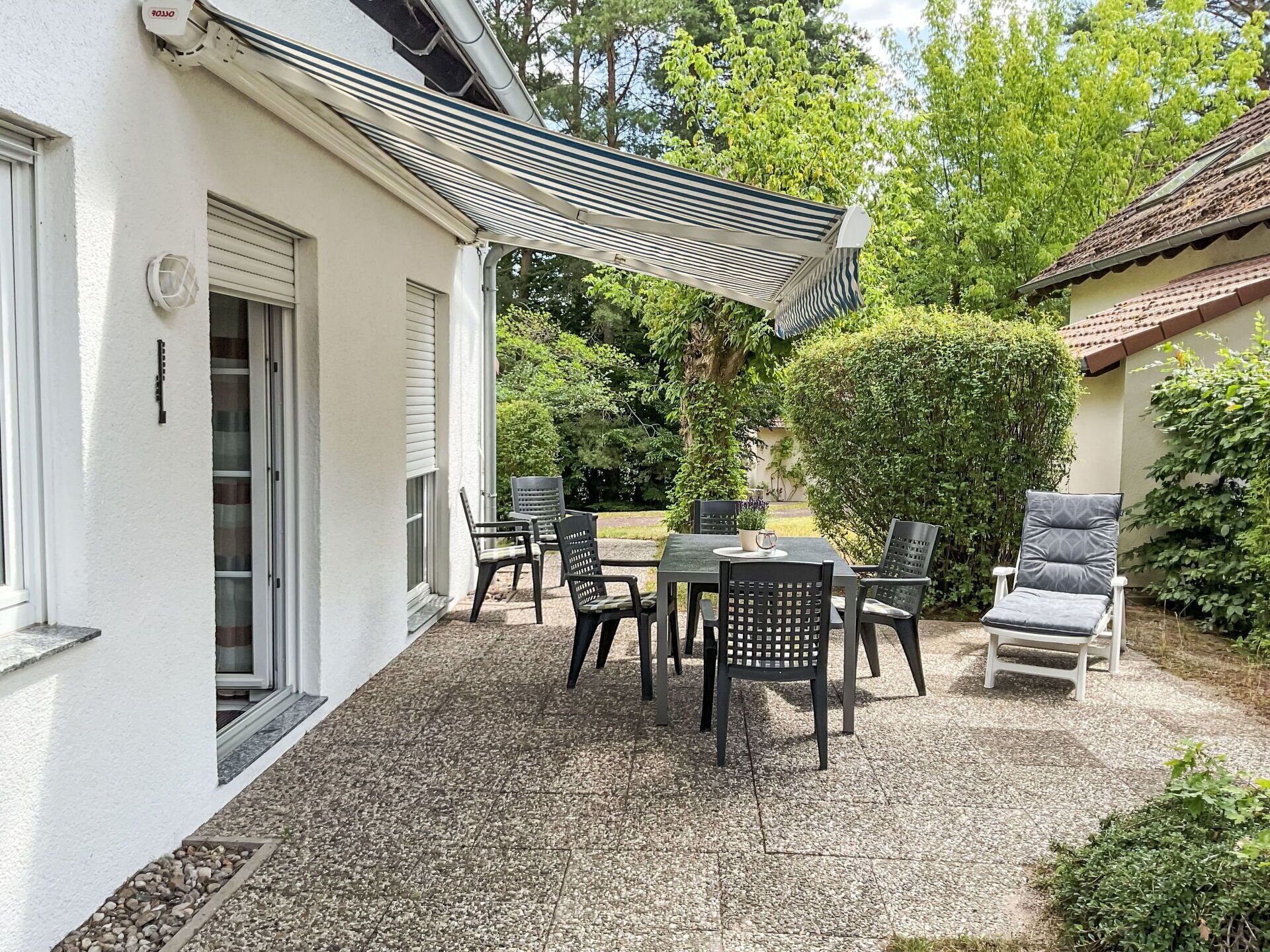 Un espace patio aménagé avec du mobilier d’extérieur, une pergola et une haie.