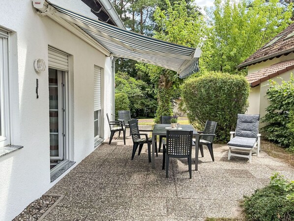 A patio area with outdoor furniture, a pergola, and a hedge.