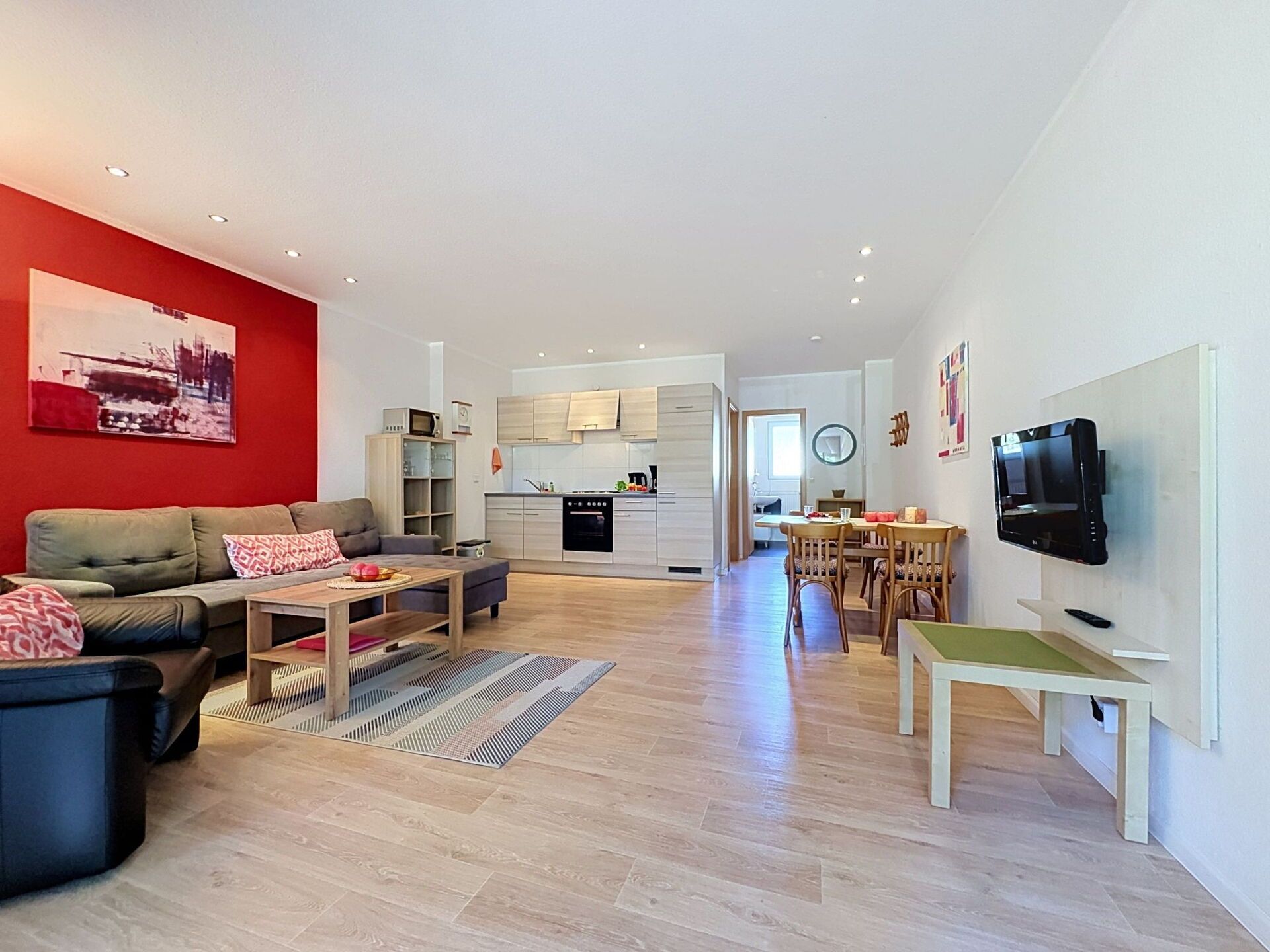 A modern living room with a sofa, coffee table, and a red accent wall.