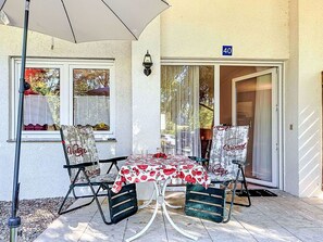 An outdoor patio with a table and chairs, a door marked with the number 40, and a window with a curtain.
