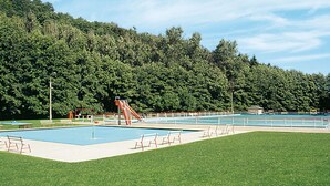 A swimming pool area with a slide, benches, and a grassy field. - Beautiful apartment for 4 guests with WIFI, TV and patio (Hettstedt)