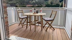A wooden deck with a table and chairs, a bottle of red wine, and a candle. - Beautiful apartment for 4 guests with WIFI, TV and patio (Hettstedt)