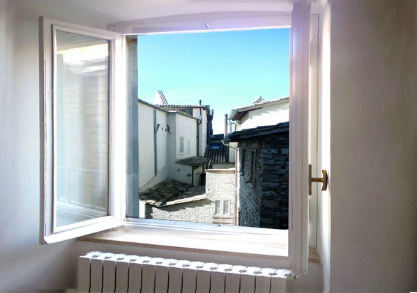 Una ventana con vista a una calle estrecha y edificios tradicionales.