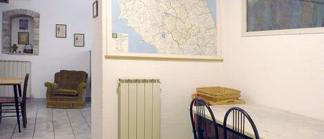 Uma área de refeições com um mapa na parede, um radiador, uma cadeira e uma mesa.