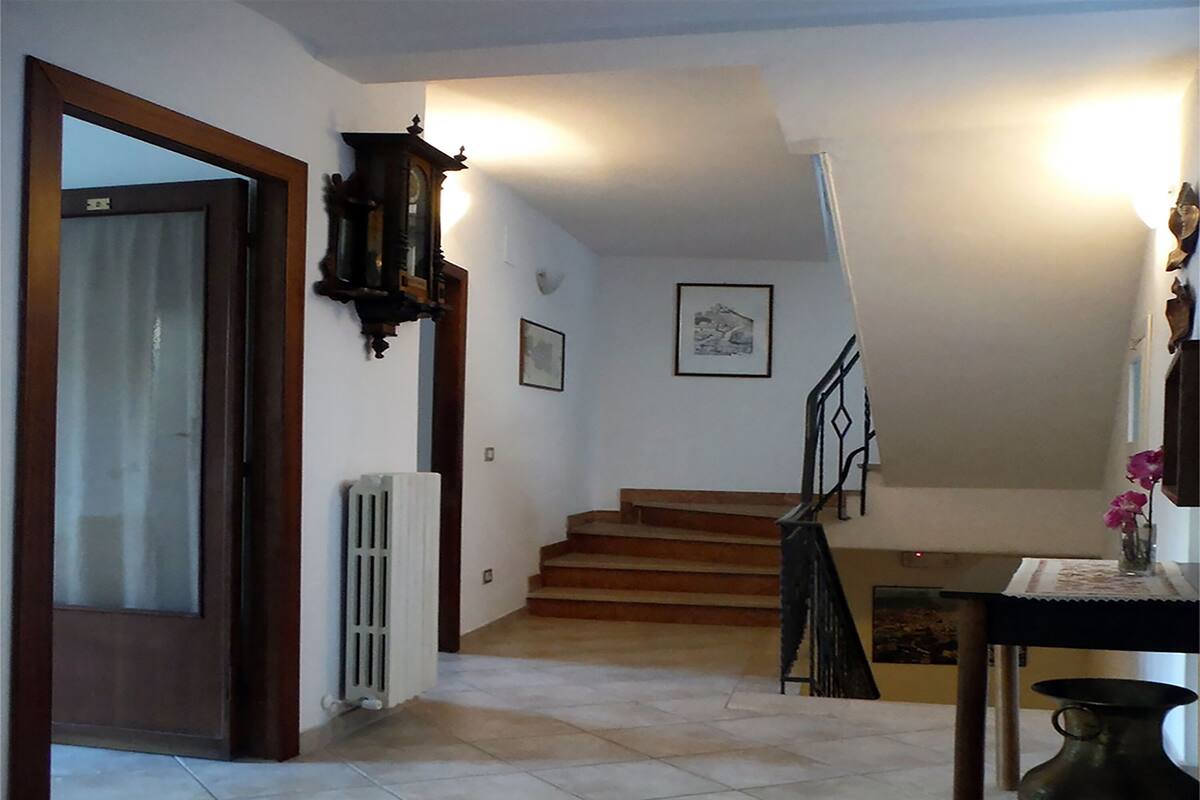 A staircase leading to a second floor, a radiator, a door with a glass panel, and a wall-mounted light fixture.