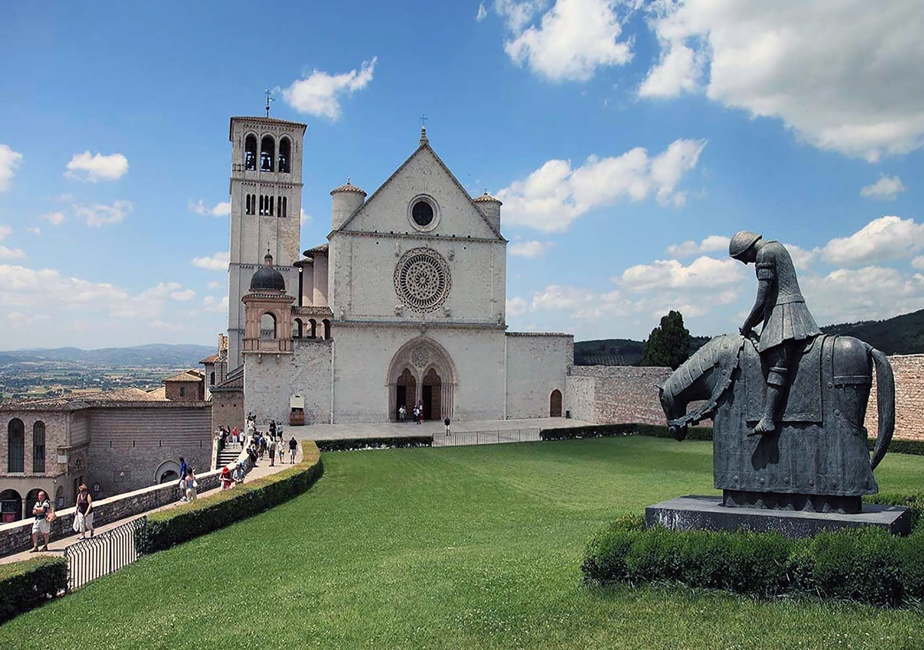 Una iglesia histórica con un campanario y una estatua de un caballero.