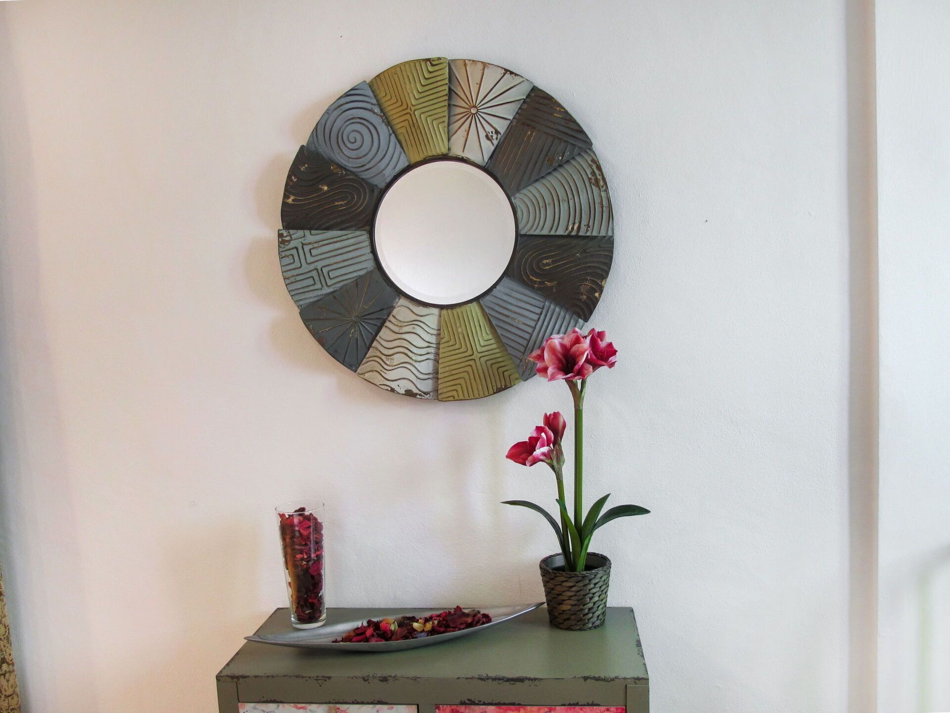 A wall-mounted circular mirror with a central reflective surface surrounded by patterned segments.