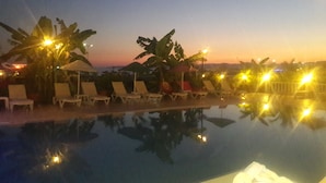 A poolside area with lounge chairs and umbrellas, surrounded by tropical plants. - Adahan Hotel (Menderes)