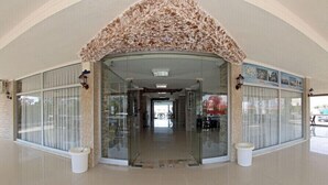 A hotel entrance with a curved glass door, a tiled floor, and a decorative leaf pattern above the door. - Adahan Hotel (Menderes)