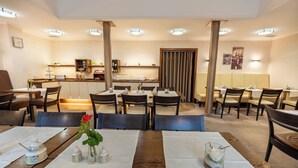 Un restaurante con varias mesas y sillas, una barra con menú, y un florero decorativo con flores en las mesas.