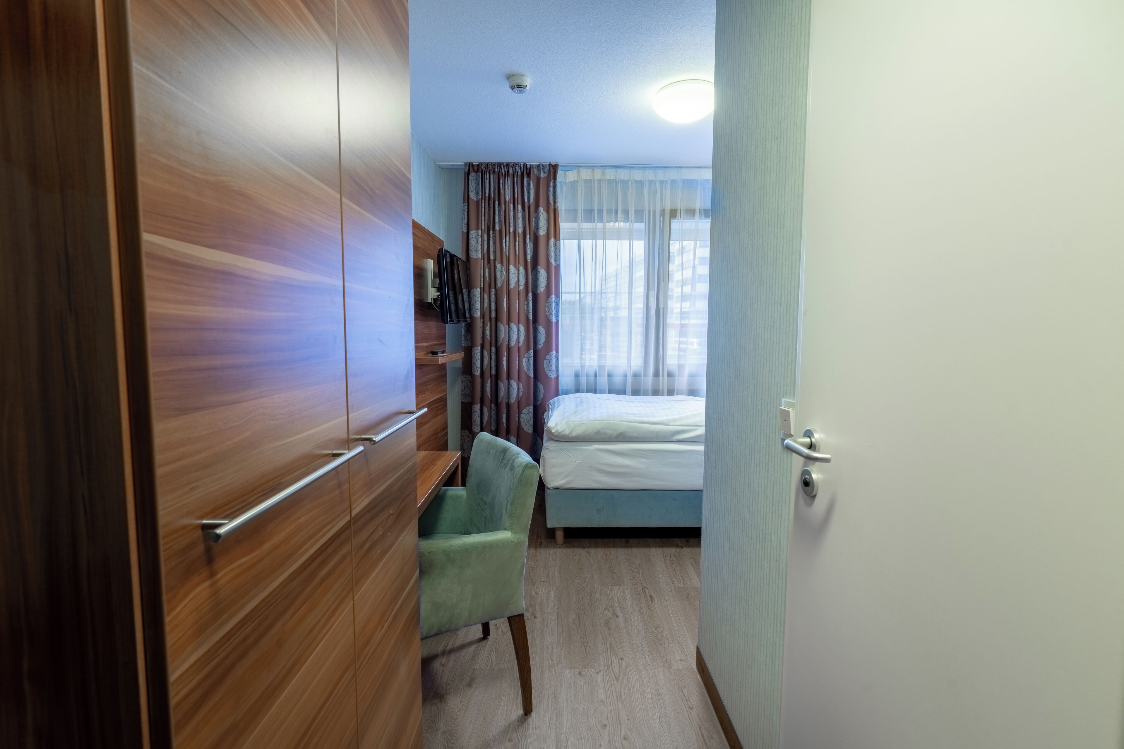 Een slaapkamer met een bed, een bureau, een stoel en een kledingkast.