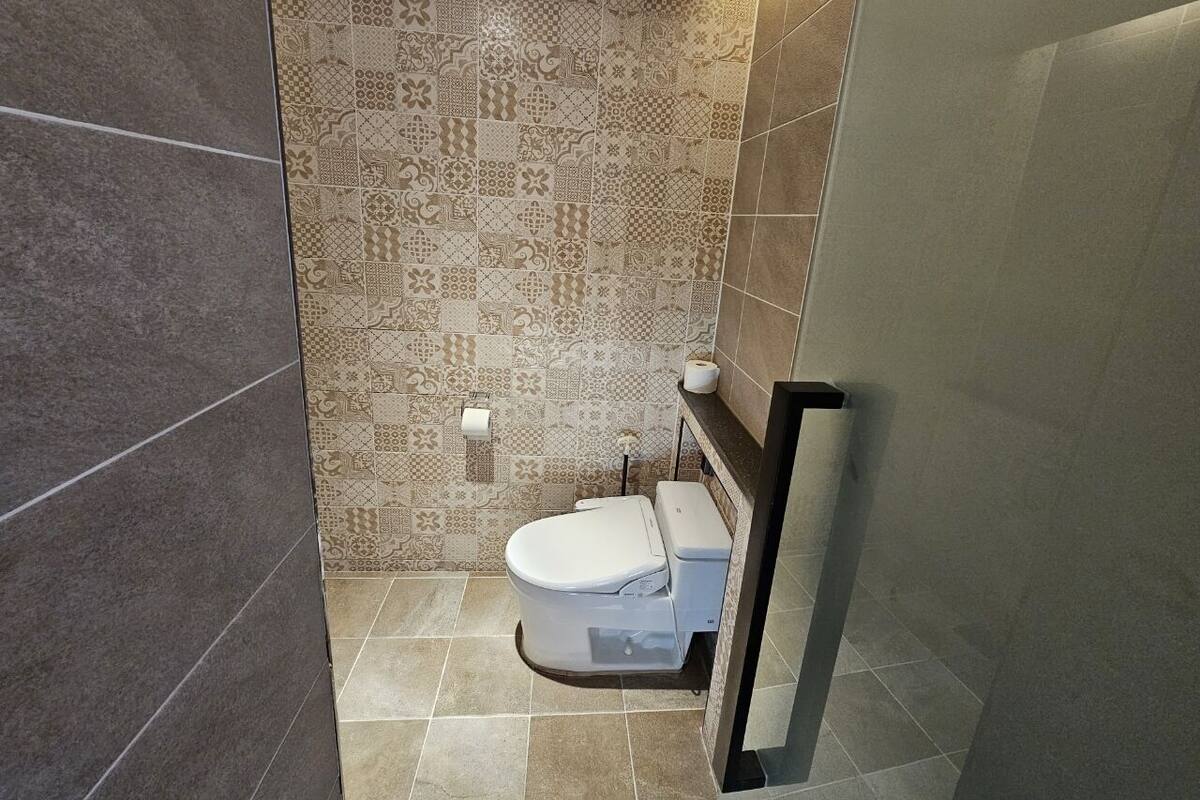A bathroom with a toilet, patterned tiles, and a towel rack.