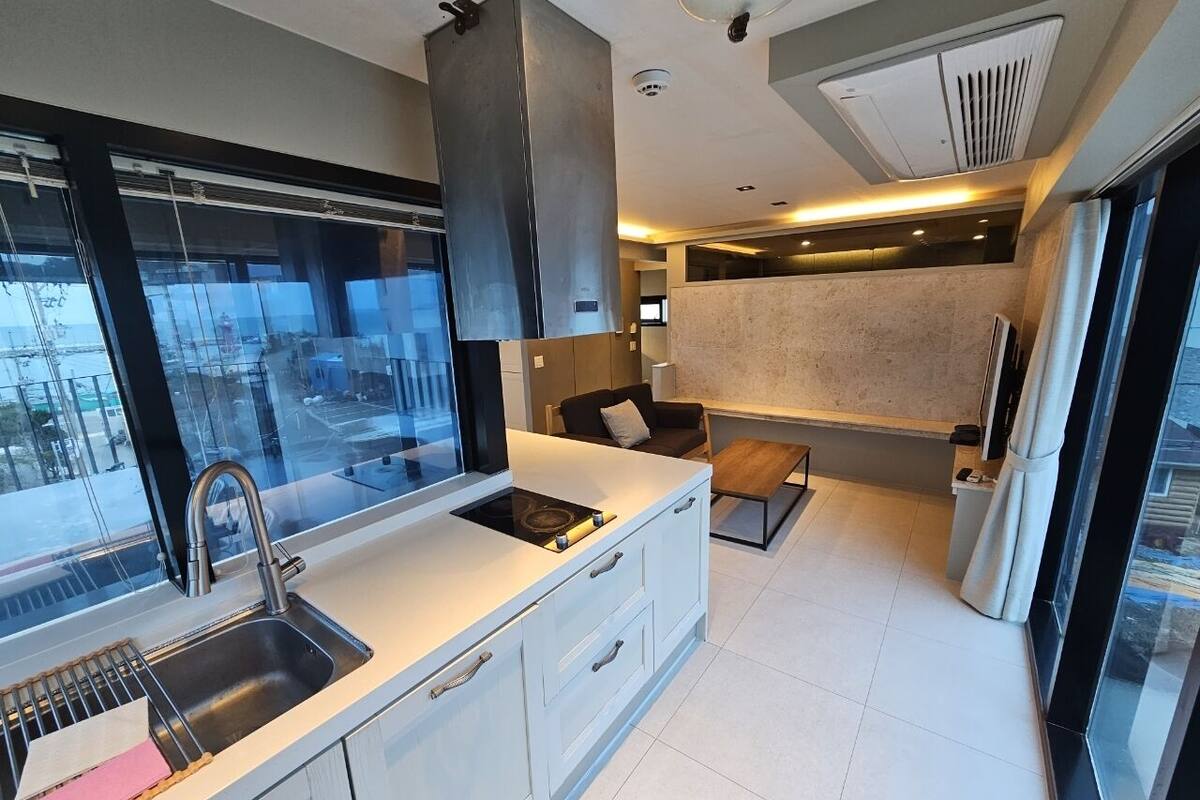 A modern kitchen with a stainless steel sink, a built-in oven, and a large window.