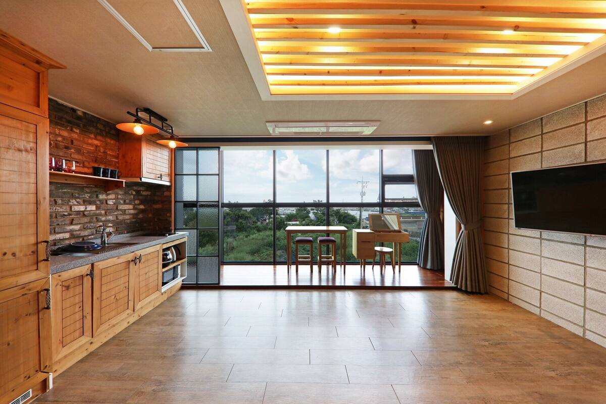 A modern kitchen with a large window, wooden cabinets, and a dining area with a table and chairs.