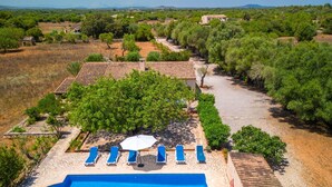 Area piscina con vasca azzurra e cristallina, circondata da piastrelle in pietra e poltrone da relax blu.