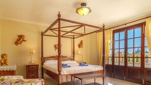 A four-poster bed with a wooden frame, a bedside table with a lamp, a bench, and a view of the outside through a large window with curtains. - Beautiful private villa for 6 people with private pool, A/C, WIFI, TV, terrace and panoramic view (Manacor)