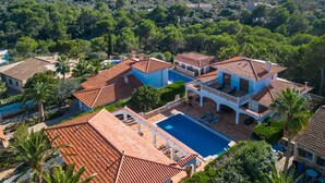 Une grande villa avec piscine, entourée d’une végétation luxuriante et offrant une vue sur la mer.