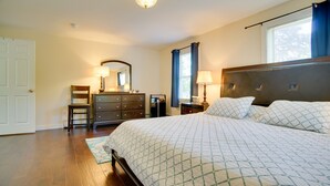 Ein Schlafzimmer mit einem großen Bett, einem Schminktisch, einem Spiegel und einem Nachttisch mit Lampe.