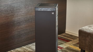A tall, dark-colored, modern-looking desktop computer in a room with a patterned carpet and a wooden wall.