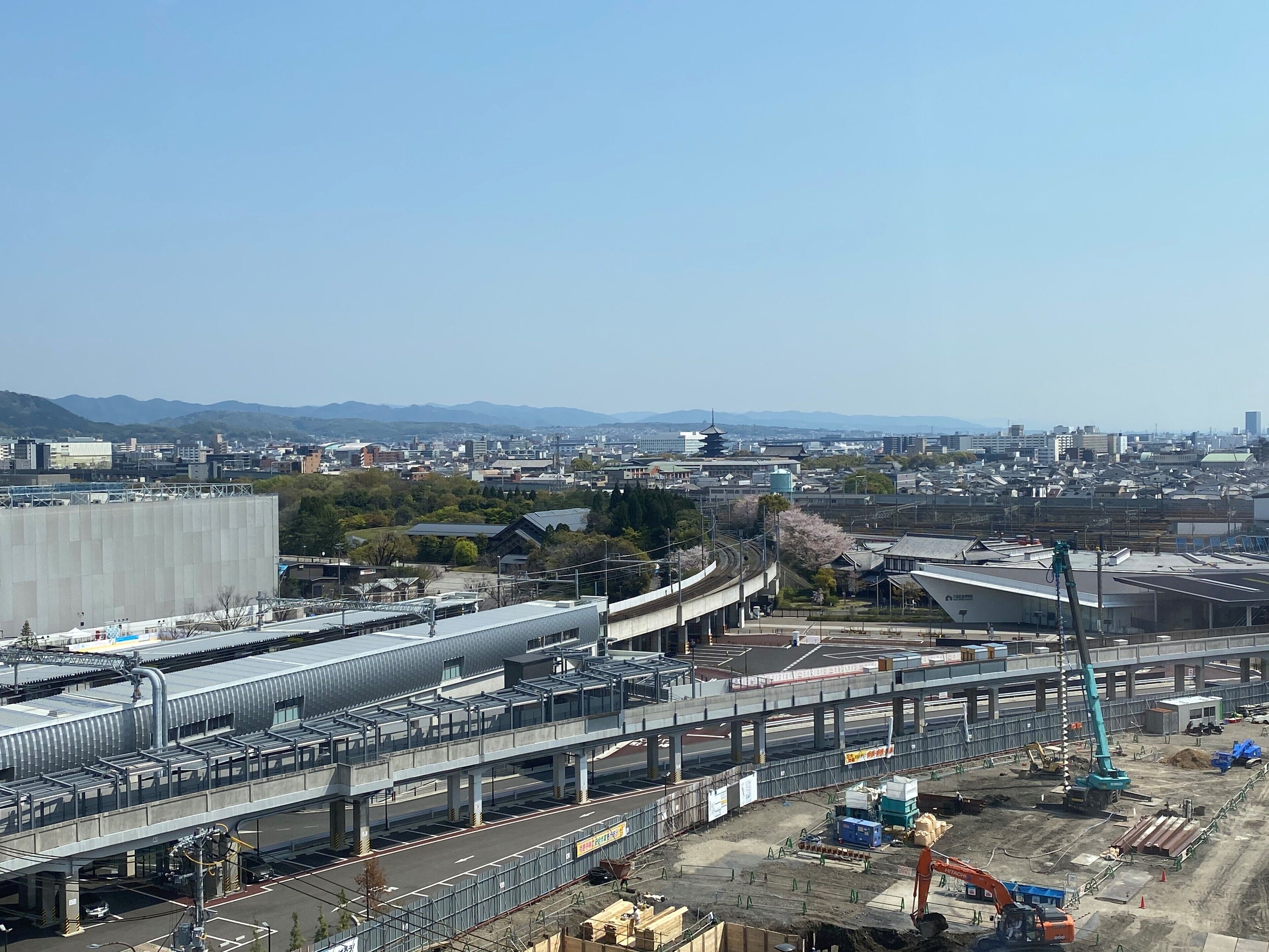 A large industrial area with construction equipment, a bridge, and a cityscape in the background.