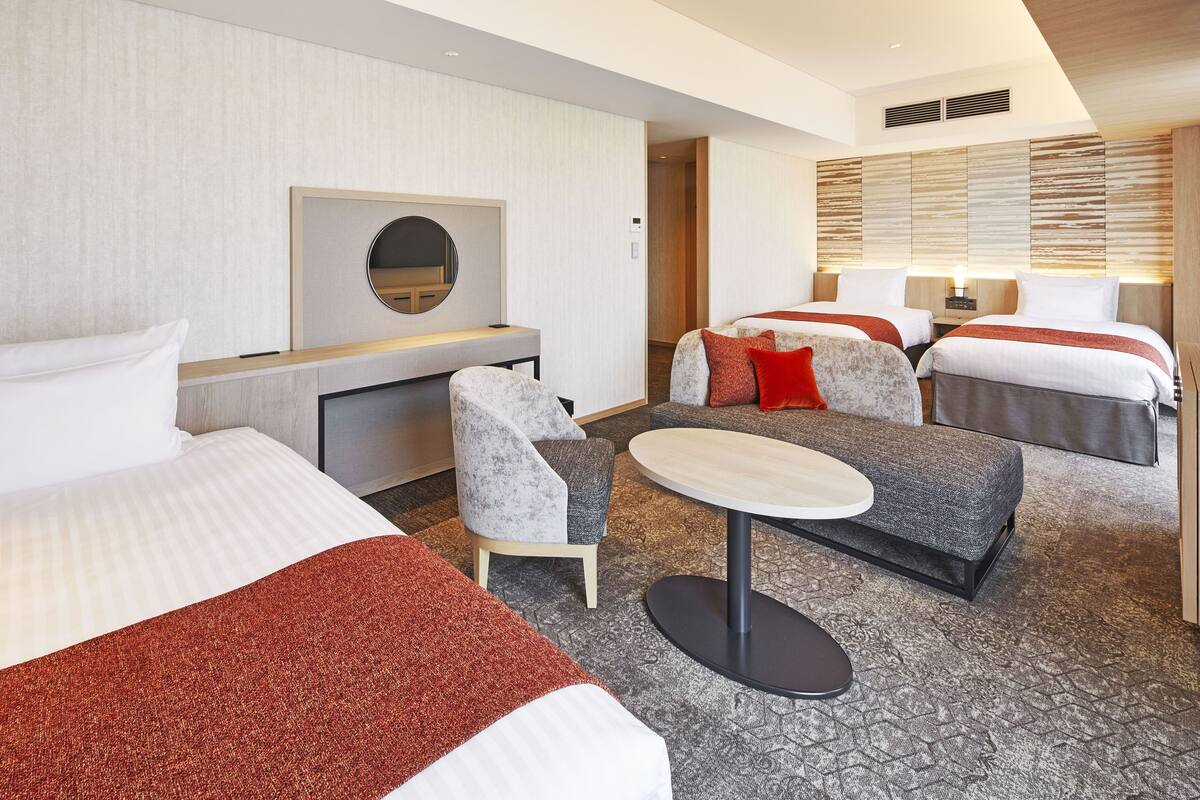 Une chambre d’hôtel avec deux lits, un bureau, une chaise et une petite table.