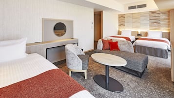 A hotel room with two beds, a desk, a chair, and a small table.