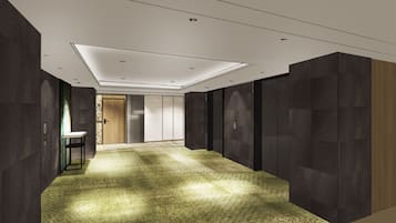 A modern hallway with dark walls, a patterned carpet, and a recessed ceiling light.