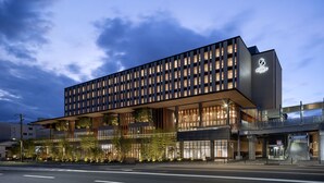 Een modern hotel met een ruitgevel, grote ramen en een opvallende ingang met een trap.