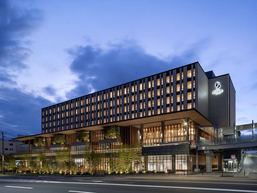 Un hotel moderno con fachada de diseño geométrico, amplias ventanas y una entrada destacada con escaleras.