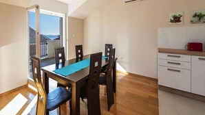 Un comedor con mesa y sillas, una cocina con armarios y vistas a través de un ventanal.