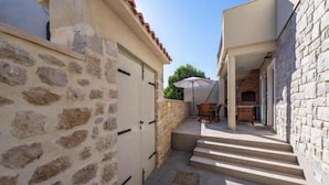 Un patio estrecho con muros de piedra, una puerta de madera y suelo de baldosas.