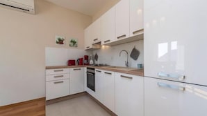 Una cocina moderna con armarios blancos, encimera de madera, horno empotrado y pileta de acero inoxidable.