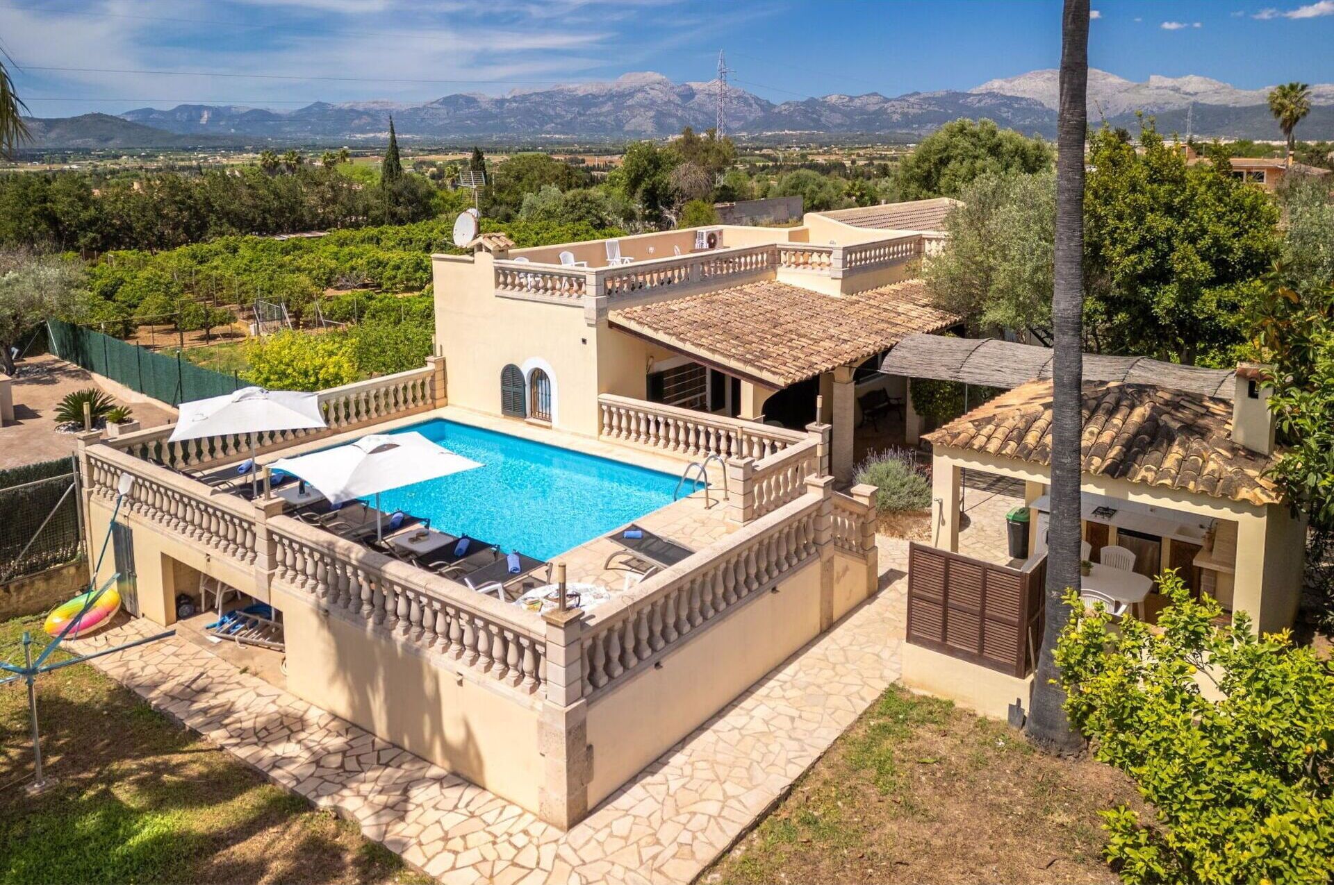 Eine Villa mit Swimmingpool, Sitzgelegenheiten im Freien und Blick auf Berge.