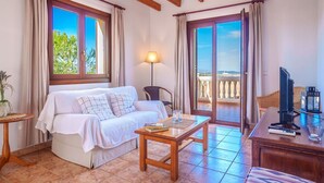 Une chambre confortable avec un lit, une table, une télévision et un balcon offrant une belle vue.