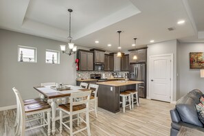A modern kitchen with a central island, white cabinetry, and a dining area with a wooden table and chairs. - Laguna Vista Resort-Style Home, Private Pool & Spa (Laguna Vista)