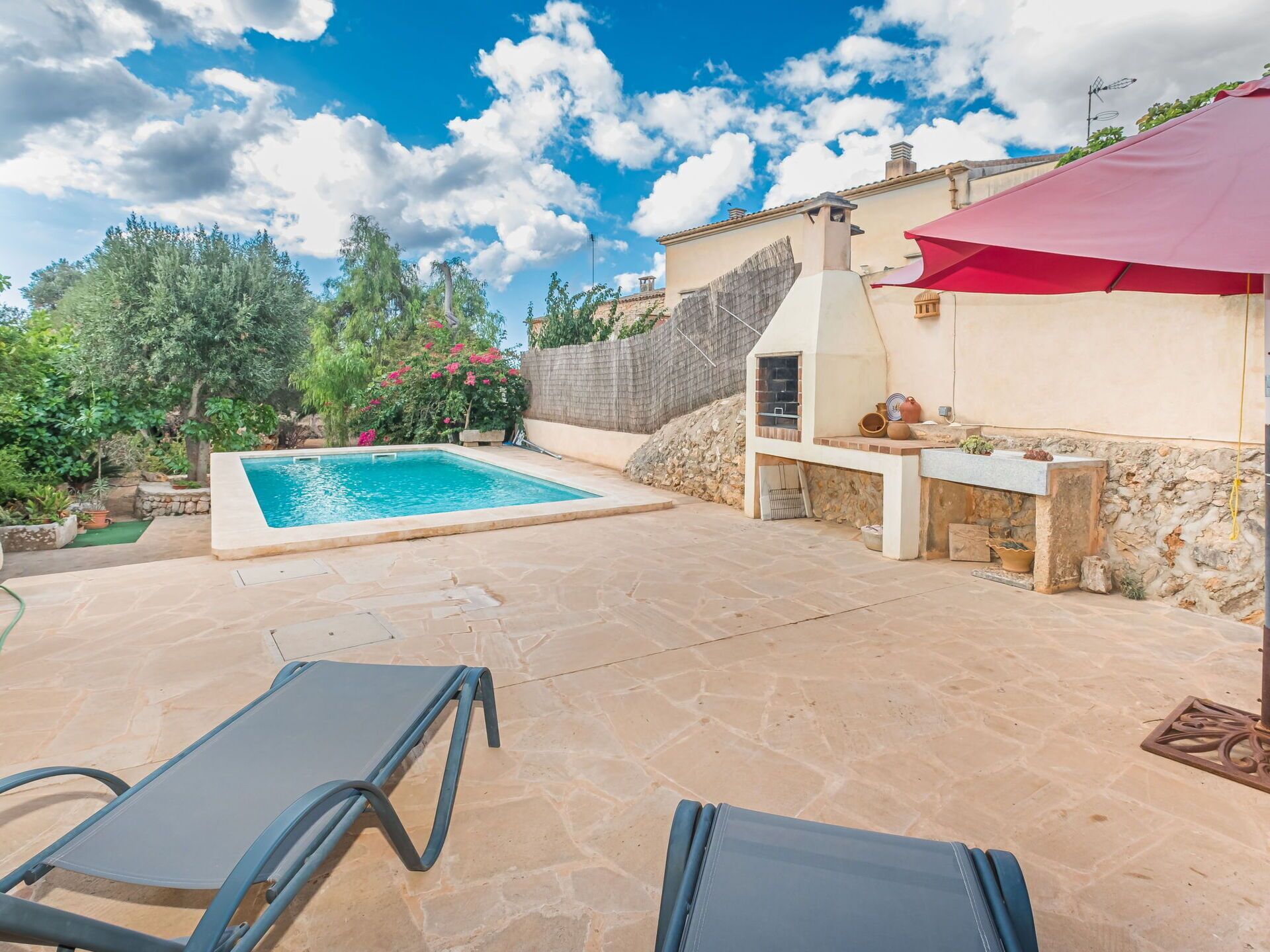 Um quintal com piscina, um alpendre de pedra e móveis de exterior.