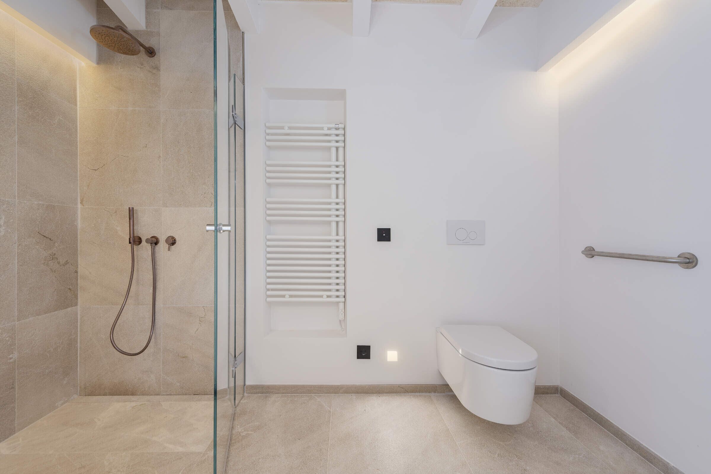 Ein modernes Badezimmer mit einer Duschkabine aus Glas, einer weißen Toilette und einem Handtuchhalter.
