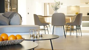 En moderne stue med sofa, rundt sofabord og spiseplads med stole.
