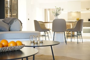Un salon moderne avec un canapé, une table basse ronde et un coin repas avec des chaises.