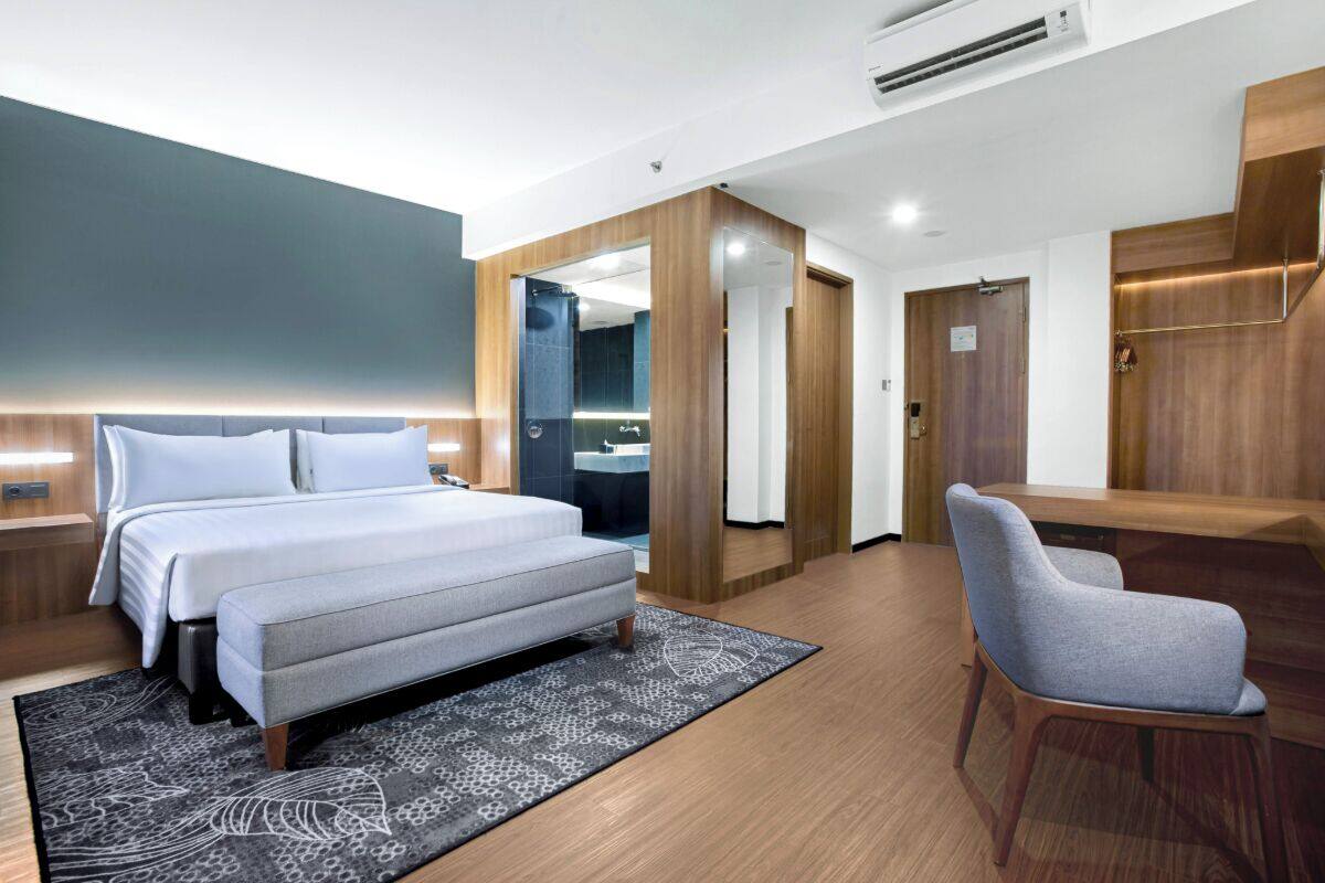 A modern hotel room with a large bed, a desk, and a shower area.