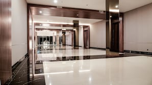 A spacious, modern hotel lobby with a polished marble floor, wooden paneling, and a bright, well-lit atmosphere. - Aston Sidoarjo City Hotel & Convention Center (Sidoarjo)