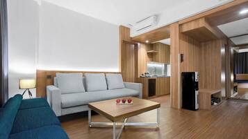 Una sala de estar moderna con un sofá, una mesa de centro y una zona de cocina con un refrigerador.