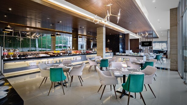 A modern restaurant with a long counter, multiple seating areas, and a visible bar area. - Aston Sidoarjo City Hotel & Convention Center (Sidoarjo)