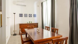 Un comedor con una mesa y sillas de madera, un aparador con azulejos decorativos y una ventana con cortinas.