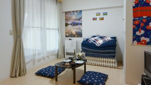 A small, neatly arranged room with a bed, a table with a few items, and a window with sheer curtains. - KIYAZA City Sapporo (Sapporo)